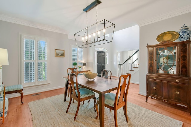 dining space featuring baseboards, visible vents, light wood-style floors, crown molding, and a chandelier