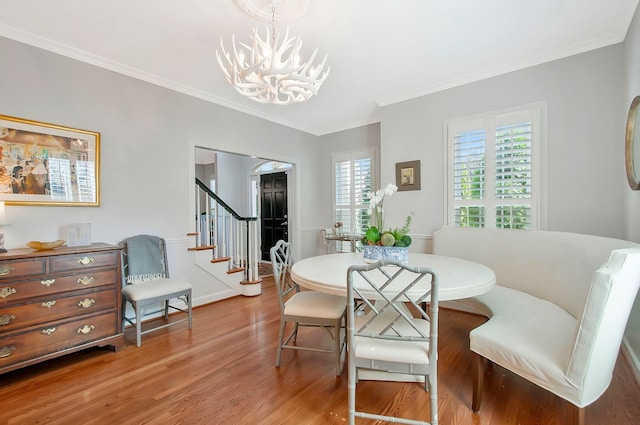 dining room featuring crown molding, stairs, an inviting chandelier, and wood finished floors