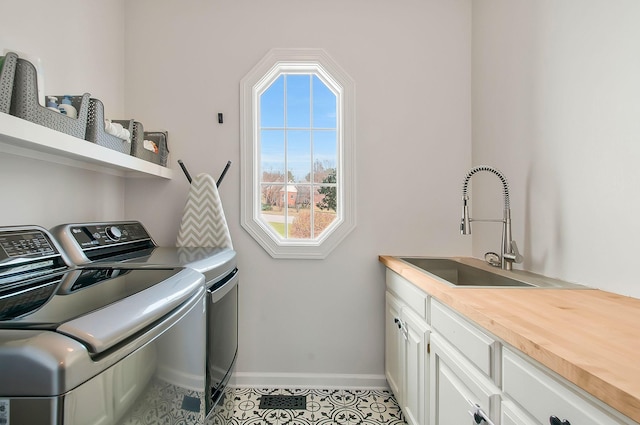 laundry room with baseboards, light tile patterned flooring, cabinet space, a sink, and independent washer and dryer