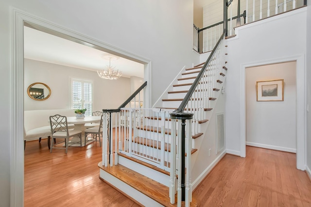 stairway with visible vents, baseboards, an inviting chandelier, and wood finished floors