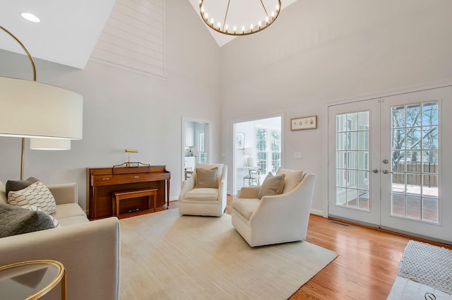 living room with visible vents, high vaulted ceiling, french doors, light wood-style floors, and a chandelier