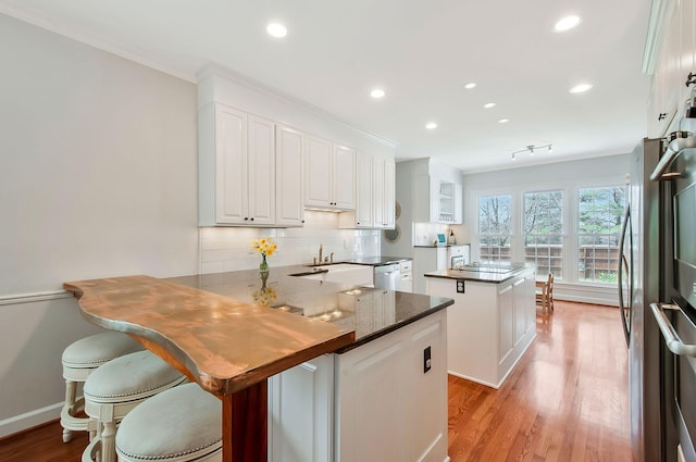 kitchen with backsplash, a kitchen island, stainless steel dishwasher, a peninsula, and white cabinets