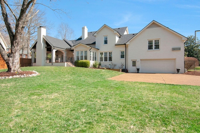 rear view of house with fence, a chimney, a yard, a garage, and driveway