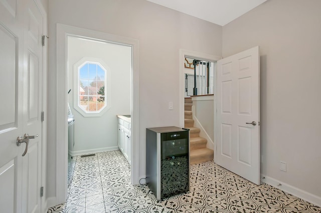 hall featuring stairs, wine cooler, light tile patterned floors, and baseboards