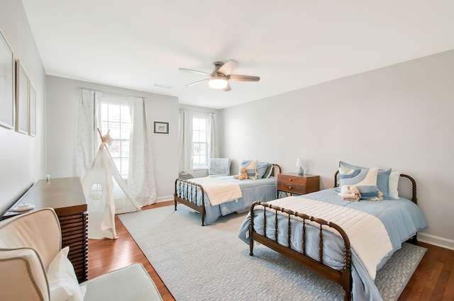 bedroom with visible vents, baseboards, wood finished floors, and a ceiling fan