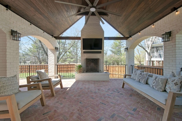 view of patio / terrace featuring fence, a ceiling fan, and an outdoor living space with a fireplace