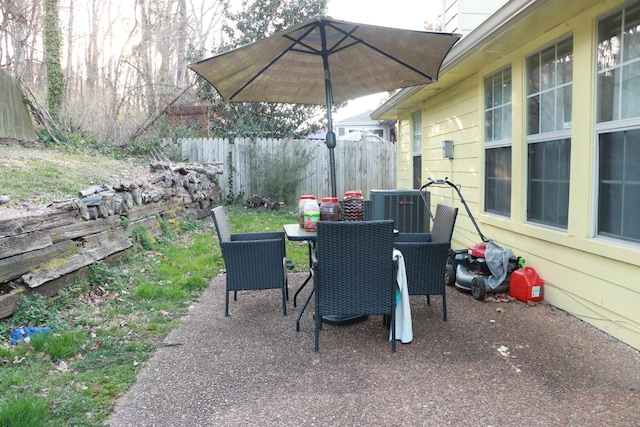 view of patio / terrace featuring central air condition unit, outdoor dining space, and fence