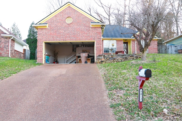 traditional-style home with aphalt driveway, a garage, brick siding, and a front yard