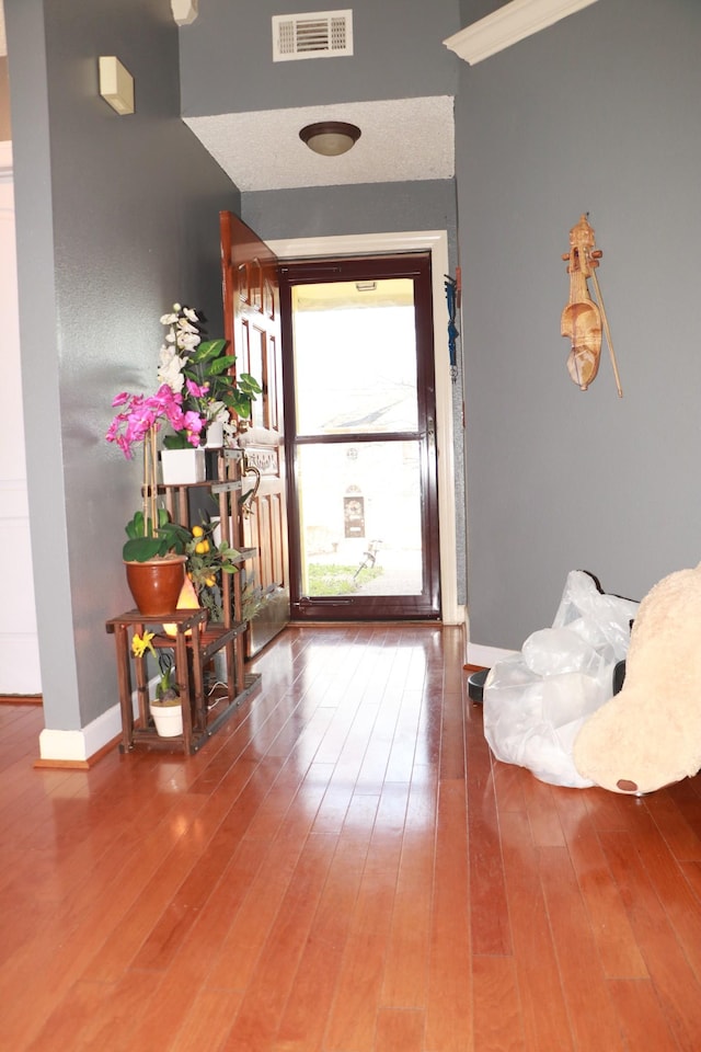 foyer featuring visible vents, baseboards, and wood finished floors