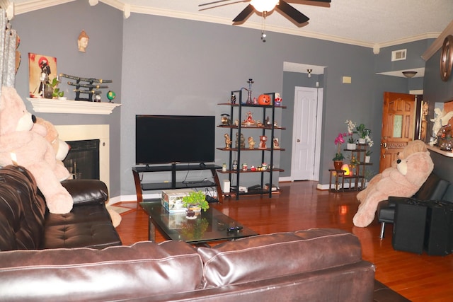 living area featuring visible vents, wood finished floors, a fireplace, crown molding, and ceiling fan