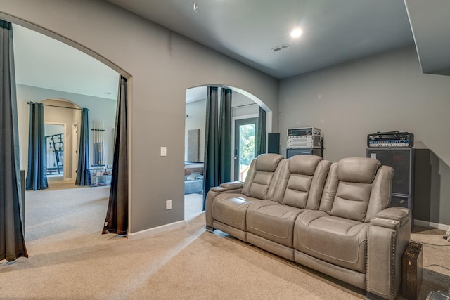 carpeted living room featuring visible vents, arched walkways, and baseboards