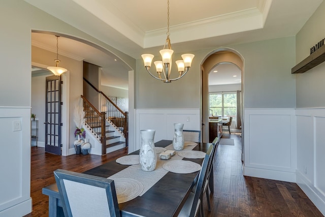 dining space with stairs, arched walkways, a notable chandelier, a raised ceiling, and dark wood-style flooring