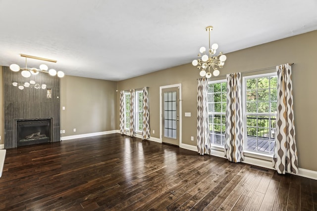 unfurnished living room featuring visible vents, baseboards, a fireplace, wood finished floors, and a notable chandelier