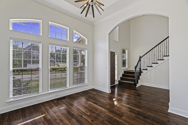 foyer entrance with crown molding, baseboards, stairs, wood finished floors, and arched walkways