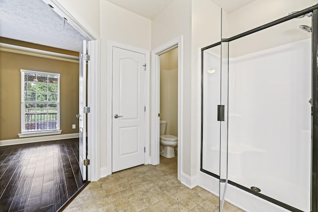 bathroom featuring a stall shower, toilet, baseboards, and wood finished floors