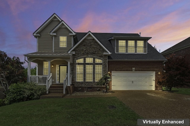 traditional home with driveway, a porch, a front yard, a garage, and brick siding