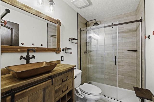 full bath featuring vanity, toilet, a shower stall, and a textured ceiling