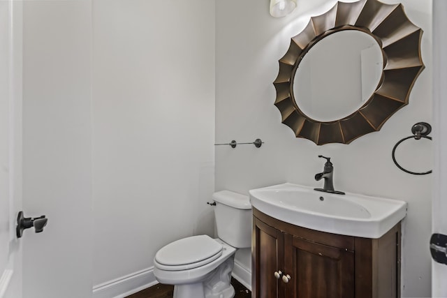 bathroom featuring baseboards, toilet, wood finished floors, and vanity