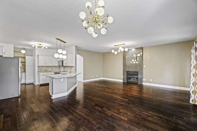 kitchen featuring light countertops, decorative backsplash, appliances with stainless steel finishes, an inviting chandelier, and white cabinets