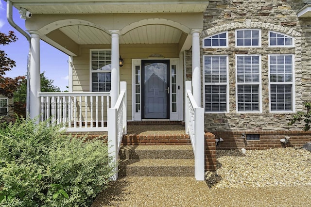 property entrance with crawl space, stone siding, and a porch