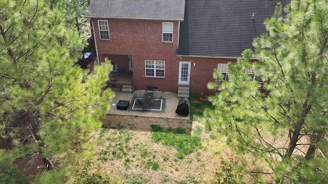 rear view of property with brick siding, a patio area, entry steps, and roof with shingles