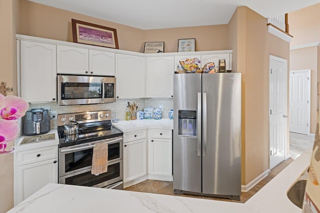 kitchen featuring light stone counters, decorative backsplash, white cabinets, and stainless steel appliances