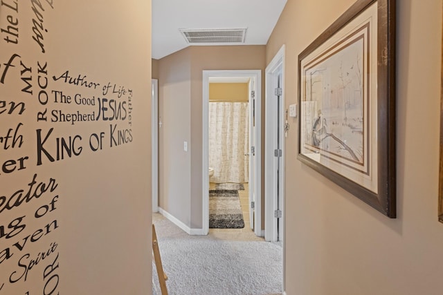 hall with carpet, visible vents, and baseboards