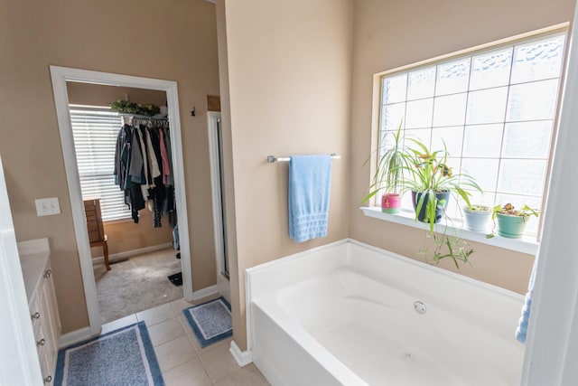 full bathroom with a bath, plenty of natural light, tile patterned flooring, and a walk in closet