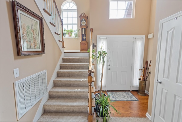 entryway with visible vents, baseboards, wood finished floors, and stairway