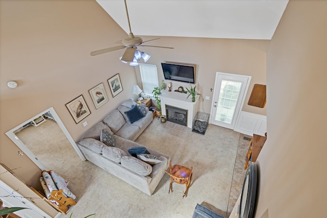 living room with lofted ceiling, a fireplace, a wainscoted wall, and ceiling fan