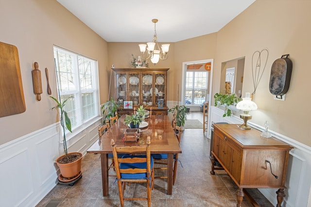 dining area featuring a wainscoted wall, a decorative wall, and an inviting chandelier