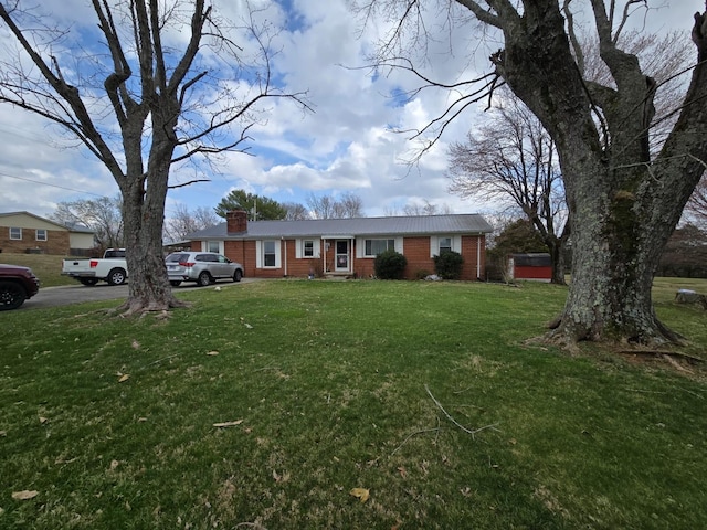 view of front of house featuring a front lawn, brick siding, and a chimney