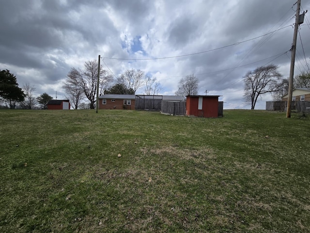 view of yard with an outbuilding, a storage shed, and fence