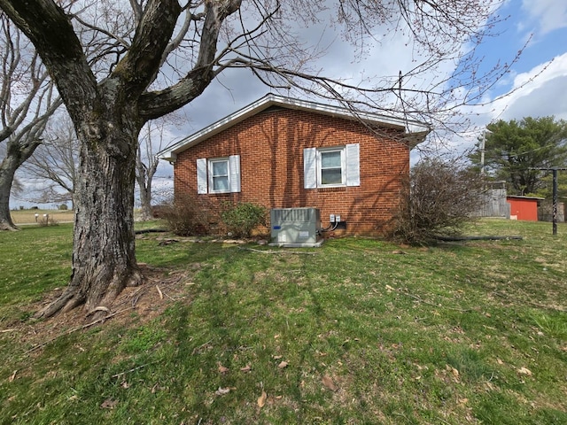 view of side of property featuring central air condition unit, brick siding, and a lawn