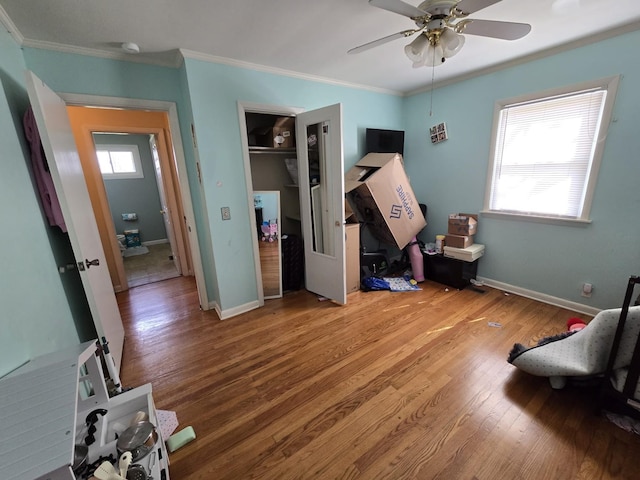 bedroom featuring crown molding, wood finished floors, baseboards, and ceiling fan