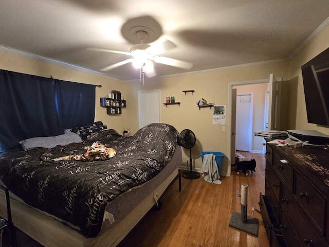 bedroom with a ceiling fan, crown molding, wood finished floors, and baseboards