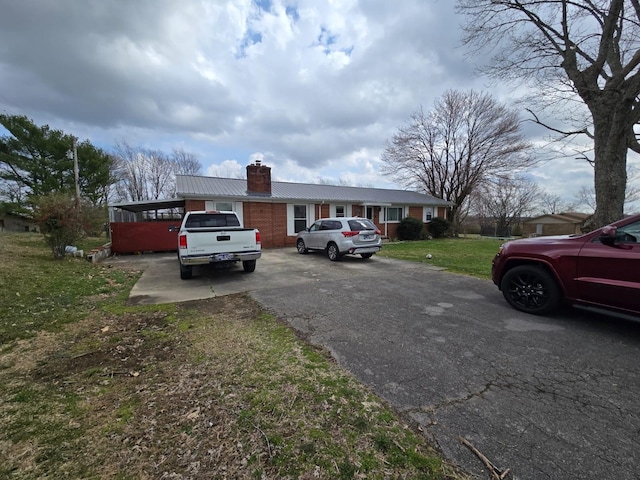 view of front of home with metal roof, a chimney, and a front lawn