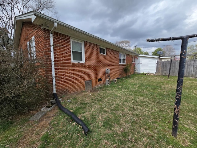 view of home's exterior featuring fence, brick siding, and a lawn