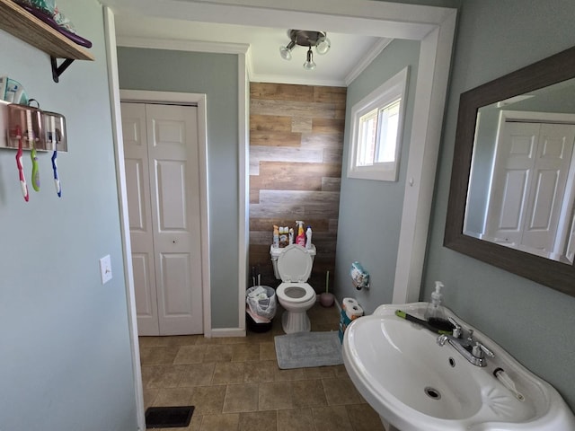 bathroom with visible vents, a sink, a closet, wooden walls, and crown molding