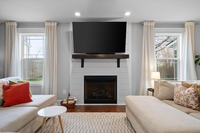 living room with a wealth of natural light, recessed lighting, a large fireplace, and wood finished floors