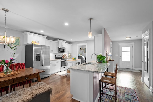 kitchen with a sink, a chandelier, white cabinets, stainless steel appliances, and dark wood-style flooring