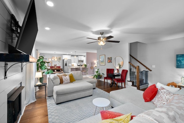 living area featuring stairway, wood finished floors, a fireplace, recessed lighting, and ceiling fan