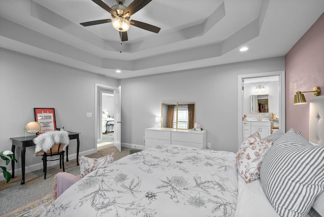 bedroom with a tray ceiling, carpet, baseboards, and ensuite bathroom