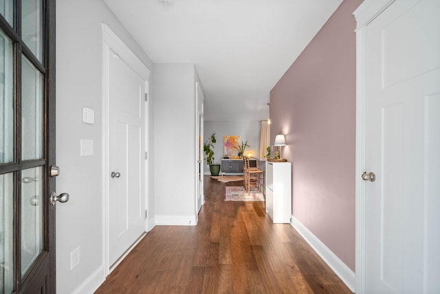 corridor with baseboards and wood finished floors