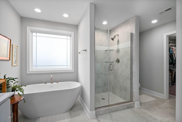 bathroom with a freestanding bath, a spacious closet, visible vents, and a stall shower