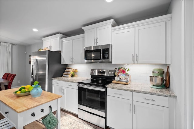 kitchen with light stone counters, decorative backsplash, recessed lighting, stainless steel appliances, and white cabinetry