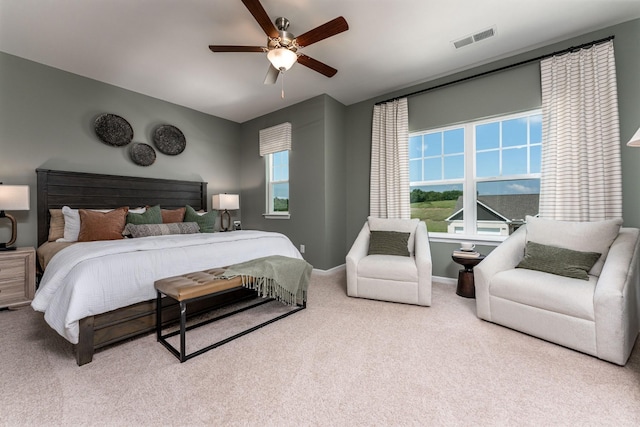 carpeted bedroom with visible vents, multiple windows, baseboards, and ceiling fan