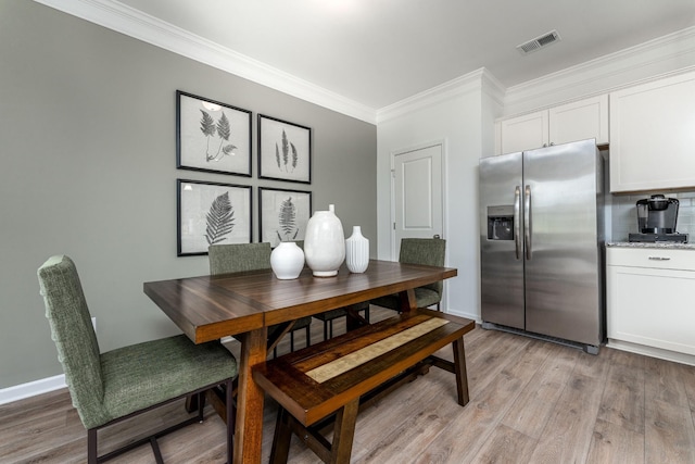 dining area with visible vents, baseboards, light wood-style floors, and ornamental molding