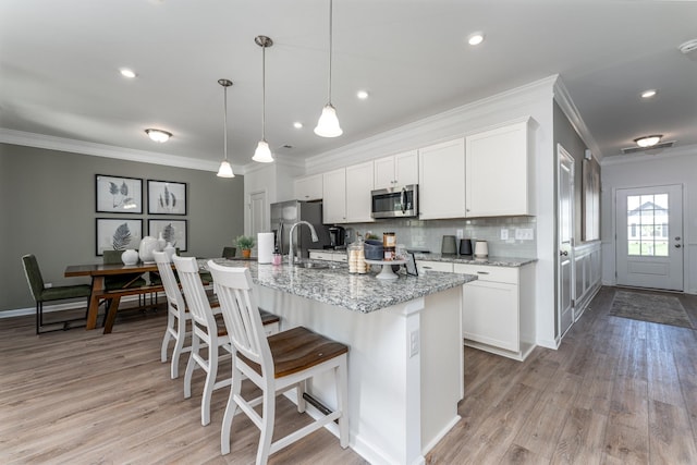 kitchen featuring decorative backsplash, appliances with stainless steel finishes, ornamental molding, and white cabinetry