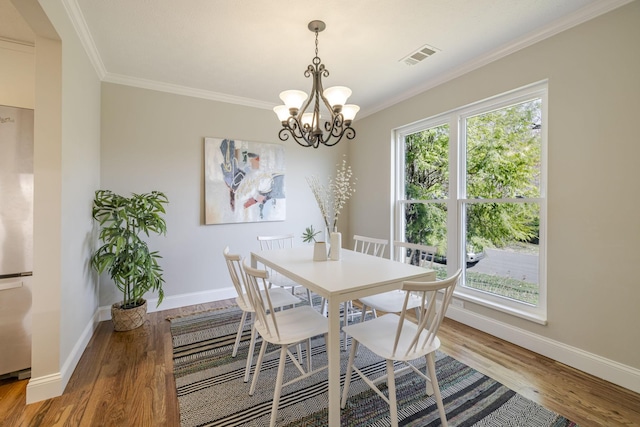 dining space featuring baseboards, an inviting chandelier, wood finished floors, and crown molding